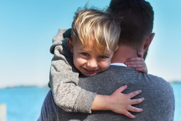 Im holding on forever. Portrait of a cheerful little boy being held by his father while they stand...