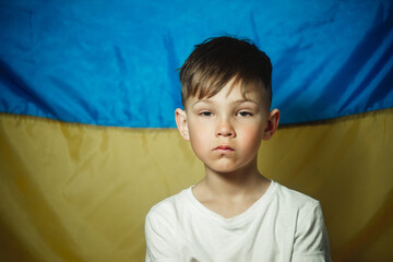 portrait of a sad boy against the background of the flag of Ukraine