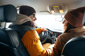 Family couple sitting in car in winter clothes iin snow forest