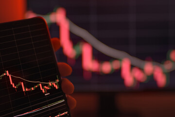 The computer screen shows a bitcoin graph. Trading online. Concept of trading online while cryptocurrency exchange rate going down with red background. Virtual currency stock market.