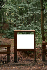 Wooden-framed old poster in the woods. Mock-up of forest guidepost. Environment friendly advertisement banner.