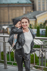 mother carries her daughter on her back while walking around the city