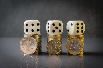 Euro, Yuan and Rubble coin stacks with dice over dark background. The idea of current economic...