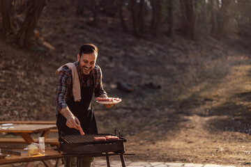 Fototapeta premium Smiling male chef putting meat on a grill.