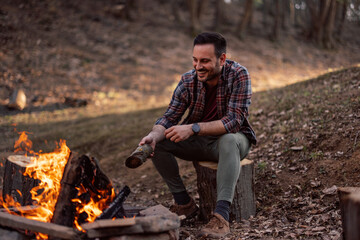 Photo of a man enjoying around the campfire, sitting alone. - Powered by Adobe