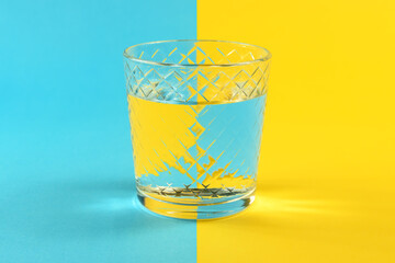 Water in glass against blue and yellow background with copy space