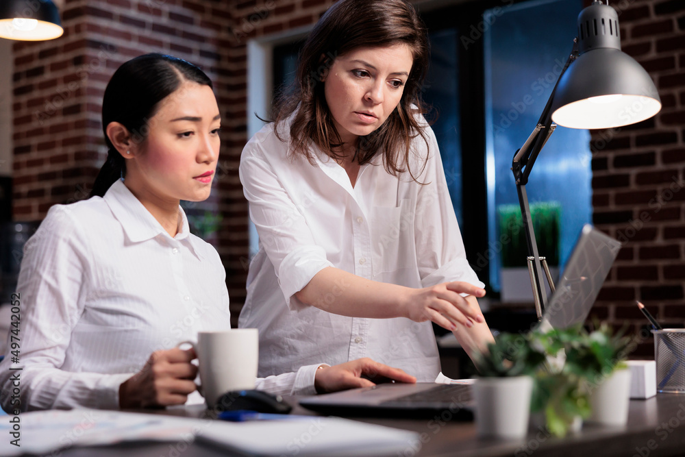 Poster Marketing company employee getting help from manager regarding wrongly issued accounting data. Multiethnic colleagues discussing about startup project documentation while looking at charts on laptop.