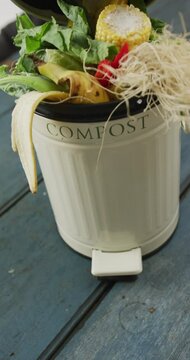 Vertical video of compost bin with organic waste on grey wooden background