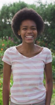 Vertical video portrait of smiling african american teenage girl in garden