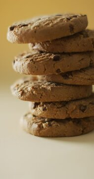 Vertical video of stack of chocolate chip cookies on yellow background