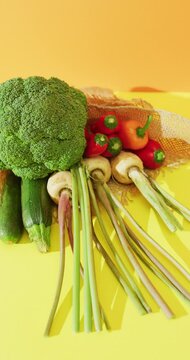 Vertical video of fresh vegetables with broccoli and peppers on yellow background