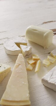 Vertical video of few types of cheese on white rustic background