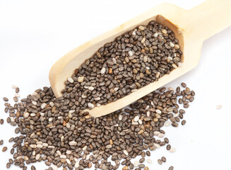 wooden scoop with Chia seeds, a superfood on light neutral surface