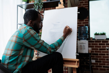 Painter artist drawing vase model on painting canvas working at illustration technique using graphic pencil during art lesson in creativity studio. Man sketching masterprice developing new skill