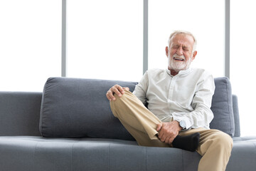 Fototapeta premium senior man suffering from knee ache on sofa