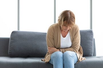 Fototapeta premium senior woman have a stomachache and holding stomach on sofa