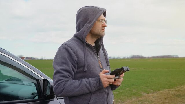 Professional aerial photographer pilot with controller for drone in field near his car. Concept of including of modern technologies and digitalization