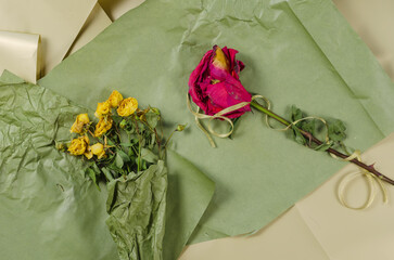Faded flowers opposite the green and beige background. A bouquet of dried yellow roses and a red...
