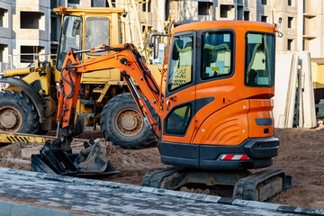 Obraz na płótnie Canvas Mini excavator at the construction site. Compact construction equipment for earthworks.