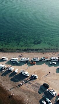 Aerial view of camper vans and cars parked on beach
