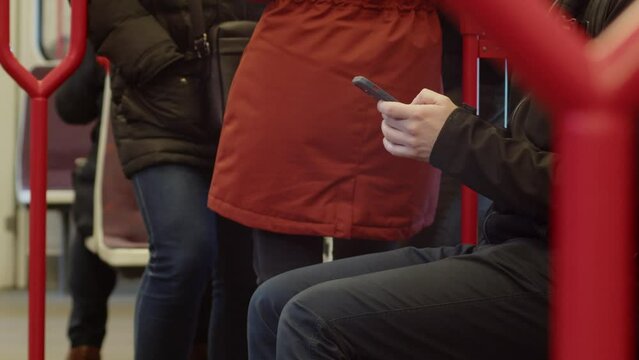 A man on the subway is texting on his cell phone. Close-up shot