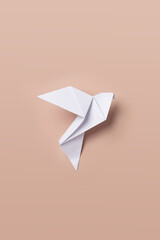 White dove origami as a symbol of peace on a pink background