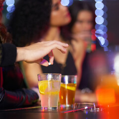 Never leave your drink alone. Closeup shot of a man drugging a womans drink in a nightclub.