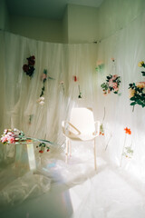 Empty white chair in sunny room with flowers on a wall.