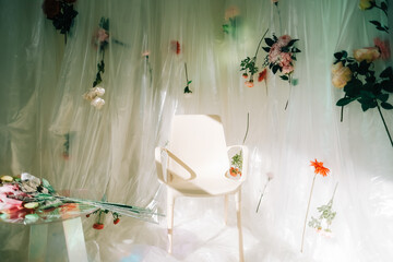 Empty white chair in sunny room with flowers on a wall.