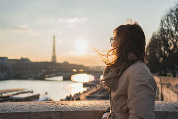 Young woman enjoying beautiful landscape view on the riverside  during the sunset in Paris.
