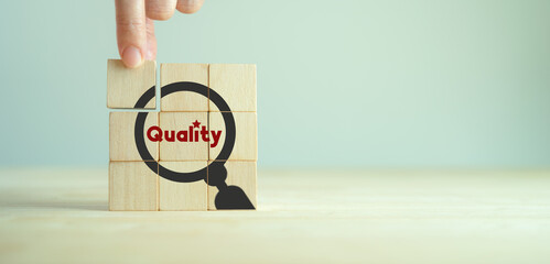 Quality warranty concept. Standardization, ISO. Hand placed wooden cubes with quality warranty icon on grey background.Used for banner and advertising premium product and service quality commitment.