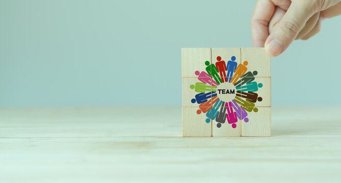 Team building and diversity concept. Work collaboration for achieving goal and successful business. Productive people skills. Hand placed wooden cubes with TEAM text and team diversity icons. Banner.
