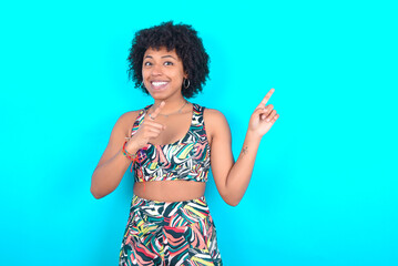 young woman with afro hairstyle in sportswear against blue background with positive expression,...