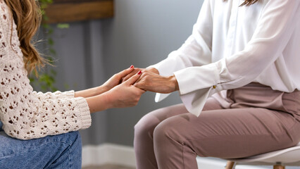 Different ethnicity female friends hold hands during confidential talk close up. Counsellor psychologist provide mental aid to patient at session in clinic, addicted patient professional help concept