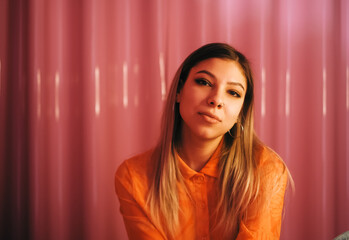 Young stylish attractive caucasian woman posing in a room with pink walls.