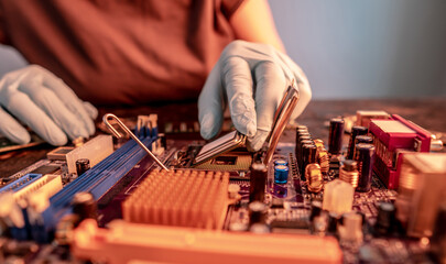 Engineer's gloved hand is holding the CPU chip on the background of the motherboard. High-tech...