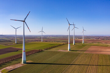 Wind farm with tall wind turbines in rural landscape as aerial shot