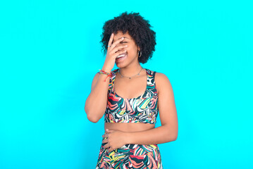 Charismatic carefree joyful young woman with afro hairstyle in sportswear against blue background...