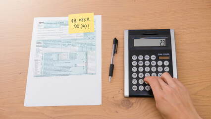 18 April 2022 Tax Day 1040 form with calculator and pen on table.