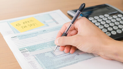 18 April 2022 Tax Day 1040 form with calculator and pen on table.