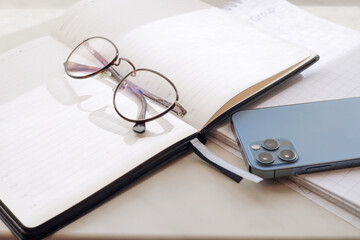 Working office table. On the table is a diary, glasses, a mobile phone.