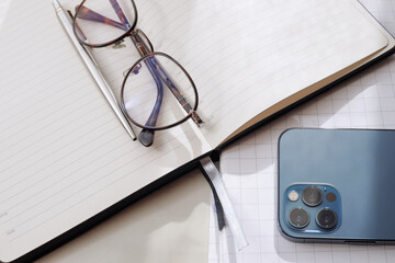 Working office table. On the table is a diary, glasses, a mobile phone.