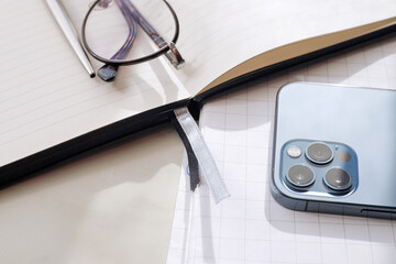 Working office table. On the table is a diary, glasses, a mobile phone.