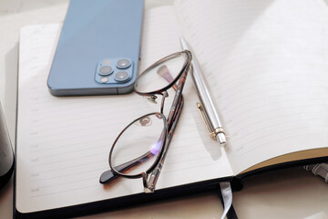 Working office table. On the table is a diary, glasses, a mobile phone.