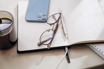 Working office table. On the table is a diary, glasses, a mobile phone.