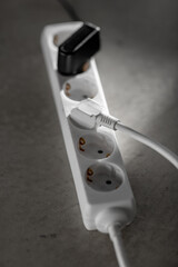 electricity, energy and power consumption concept - close up of socket with plugs and charger on concrete floor