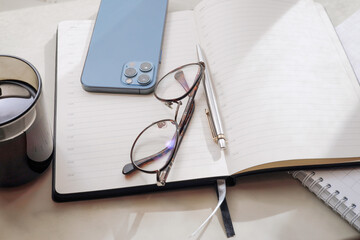 Working office table. On the table is a diary, glasses, a mobile phone.