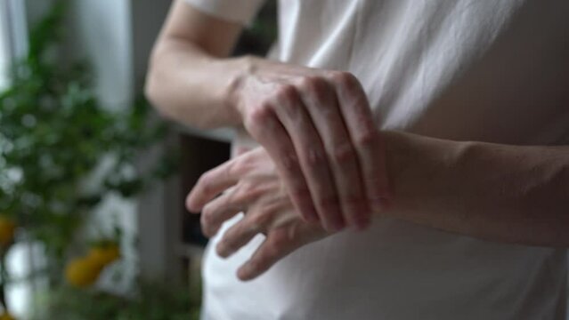 Closeup of man arms massaging painful wrist after work on laptop computer at home, suffering from weakness and tingling, carpal tunnel syndrome, arthritis, neurological disease. Numbness of hand