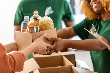 charity, donation and volunteering concept - close up of volunteers giving box of food at...