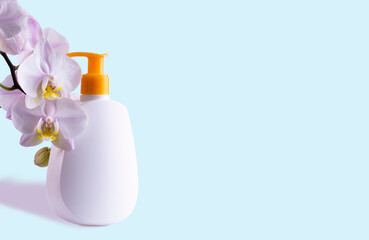 White bottle with hygiene or skin care product and branch with orchid flowers on blue background, space for text